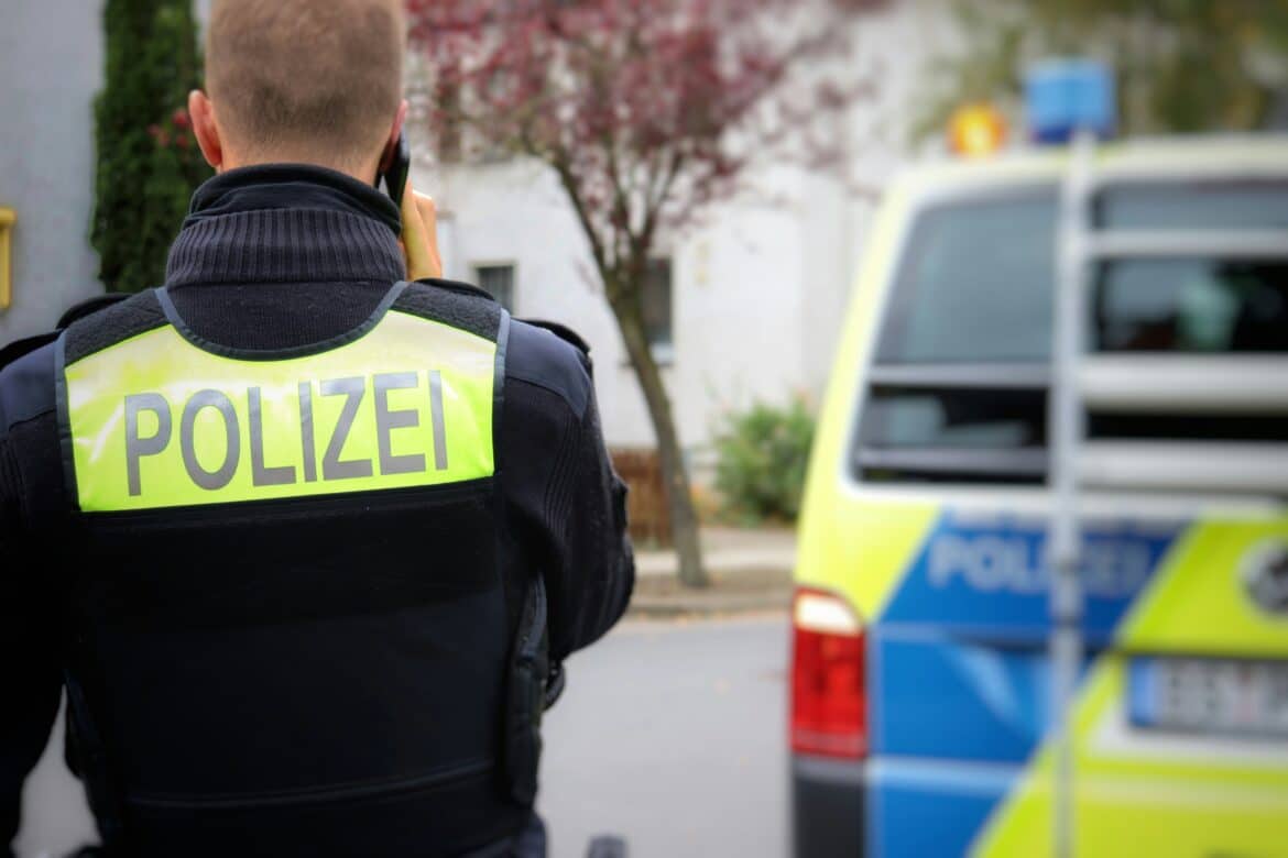 Polizeibeamte (von hinten), im Hintergrund ein Streifenwagen
